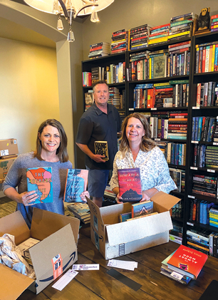 Genevieve Seivert, far left, started selling books online through her business The Bookaholic’s Outlet in January of last year. Pictured with her are her husband, Paul, and friend and neighbor Trina Cook, who helps her put books in boxes to ship to customers (submitted photo). 