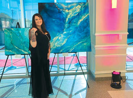 Holly Anderson, a local artist, stands by some of her artwork that is on display at The Madison Center for the Arts’ new The Gallery at The Madison, which opened last month. Her pieces, as well as the work of Alisha Marie Anglin, will be featured at this gallery through Sept. 30 (photo by Colleen Sparks).