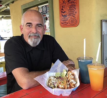 John Lichtenberg, owner of The Beach House, serves up favorites on the menu – a trio of tacos filled with spicy shrimp, grilled fish and batter-fried fish, along with fruity smoothies (photo by Marjorie Rice).