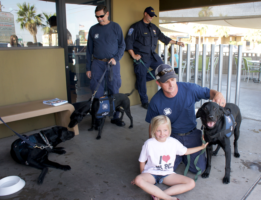 Teams from Arizona Search Dogs recently visited Scramble restaurant for a fundraising event. The breakfast-all-day eatery at 9832 N. 7th St. donated 15 percent of all sales on the night of May 29 to the nonprofit group, while search dogs and their handlers visited with restaurant patrons outside. Among them were, clockwise from left: Moose, who sniffs noses with new trainee Rainey with handler Don Peyton of the Phoenix Fire Department; Mike Rohme of the Phoenix Police Department with his dog, Ruger (out of frame); Hoss, with his handler Dana Medlin of the Phoenix Fire Department and Dana’s 9-year-old daughter, Addie. Proceeds from the evening will be used toward paying for the training and care of two new search dogs: Free and Rainey. There are less than 20 search dogs currently in the organization, the majority of them being black Labrador retrievers. For more information, visit www.ArizonaSearchDog.org.