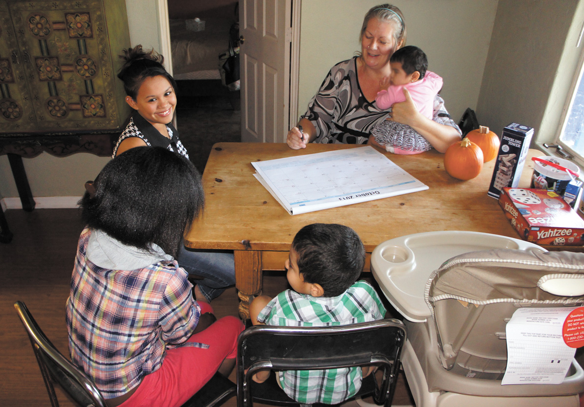 Adoptive and foster parent Michelle Harrington plans out the week’s activities with her adopted daughter, Luz (left), and her three foster children (photo by Teri Carnicelli).