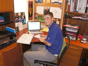 North Central youth Jeffrey Miller goes to an online high school in order to travel around the country to play competitive golf. His work station at home contains a laptop, books, and inspirational photos—and at least one familiar college logo (photo by Teri Carnicelli).