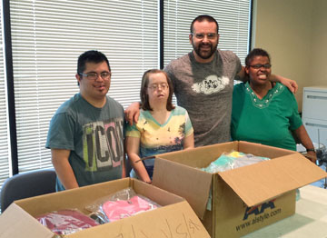 Robert Thornton, second from right, owner of Paper Clouds Apparel, gets help packaging up his T-shirts from special needs adults, from left: Antonio, Jennifer an Diamond. Last names are not used to protect their privacy (photo courtesy of Paper Clouds).