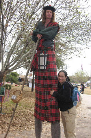 North Central resident Kezia Allen tries to cheer up a sour Scottish stilt walker with a hug during the annual Arizona Scottish Gathering & Highland Games (photo by Teri Carnicelli).