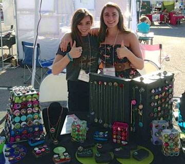 Ileyna (left) and twin sister Flori Witenstein, both seniors at Sunnyslope High School show off some of the hundreds of “Whoopies” they've made and sold at the Sunnyslope Art Walk (on Facebook, Whoopies-Caps with a Cause). They decorate the bottle caps and then sell them to raise money and awareness of the need for everyone to be vaccinated against Pertussis, also known as whooping cough—which they both came down with in the summer of 2008 (submitted photo).