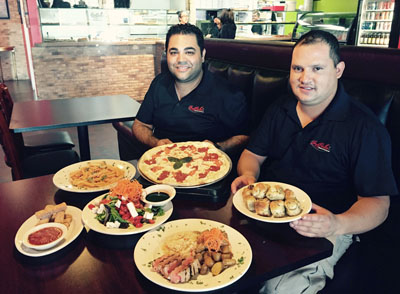 Nathan Uveydo, owner of La Bella Pizzeria and Restaurant, and manager Daniel Herrera show off a plethora of dishes they serve to an ever-growing customer base. Pictured are the Margarita pizza, Penne A La Vodka, Garlic Knots, Mozzarella Sticks, Grilled Tuna and the Insalata Bella (photo by Patty Talahongva).