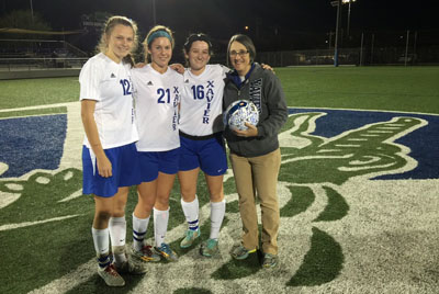 Xavier senior soccer players Kelly Harris, Amanda Lane and Kendall Ward present Gators athletic trainer Laurie White with an autographed ball at halftime of a match against Mountain Pointe last season (submitted photo).
