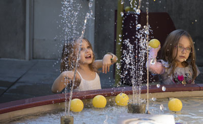 Two girls beat the heat by enjoying the water play area in the interior courtyard at the Arizona Science Center, which is offering free general admission Sept. 19-20 (photo by Alexis Macklin).