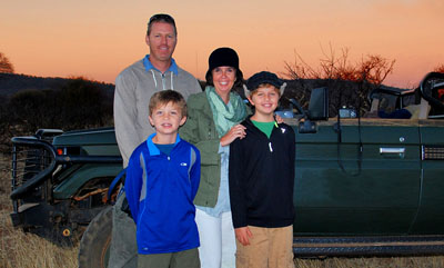 Enjoying a spectacular sunset at the Madikwe Game Reserve in South Africa are the globe-trotting Simmons family, clockwise from top left: dad Jeremy, mom Carrie, and sons Nathan and Seamus (photo courtesy of Travel With Kids).