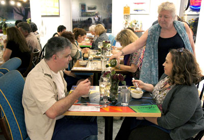 Virgina Senior, co-owner of Urban Beans café and wine bar, pours a glass of Australian pinot grigio for Amber Manzer and her husband, Jarrod, during the Aug. 20 five-course wine dinner held at the eatery. The Manzers enjoy the second course of the Asian-inspired meal, a Tom Kha-Gai soup with kafir leaves. Next month’s wine dinner on Sept. 17 has an Italian theme (photo by Teri Carnicelli).
