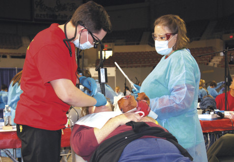 Dr. Matthew Lonier, DDS, and Dental Assistant Stephanie Nader of North Central Family Dentistry prepare a woman’s tooth for a filling during the fourth-annual Dental Mission of Mercy event, held Dec. 11-12 at the Veteran Memorial Coliseum. Dr. Lonier spent the weekend working on restorative dental care, such as fillings and bonding (photo by Teri Carnicelli).