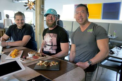 CoR Tapas chef Michael DeFilippis, left, and owner Cory Chan, right, visit with regular patron Truett Fuentes as they discuss three popular menu items: the paella, with scrimp, calamari, Valencia rice and sofrito served on mussels; the Triple Delight dessert, featuring chocolate torte, vanilla crème brulée, and bread pudding; and the spicy scallops with pineapple salsa (photo by Teri Carnicelli).
