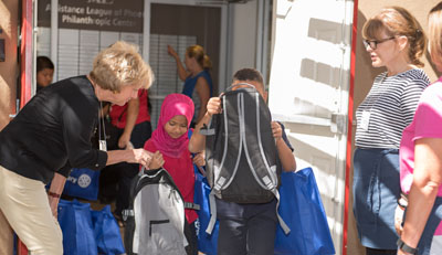 Volunteer members assist children as they leave the Assistance League’s Philanthropic Center with new school clothes, a new backpack, and toiletries. ALP’s largest program, Operation School Bell®, provides new school clothing for children in need at more than 90 Title I elementary schools in the Phoenix area (submitted photo).