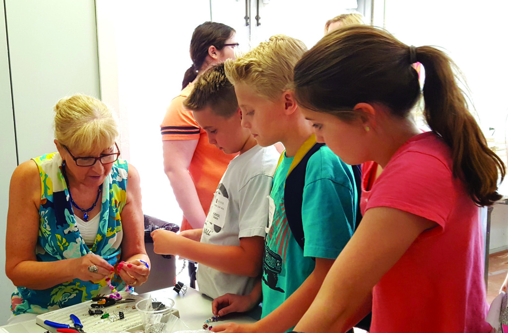 North Central resident and jewelry designer Gerri Dames, who recently launched “Gerri’s Beading Parties,” teaches a group of kids how to make their own beaded bracelets during a workshop last month at the Shemer Art Center (submitted photo).