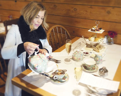Manchester, England-born Grace Unger, co-owner of Phoenix's Tuck Shop, enjoys one of the eatery's Saturday afternoon High Tea services, which includes tea served in the appropriately named "Gracie" China pattern, a selection of finger sandwiches and pastries, and an optional glass of champagne (submitted photo).
